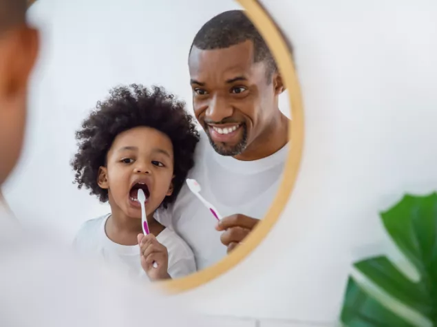 Man and child looking in mirror, brushing teeth 