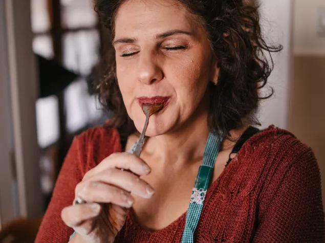 A headshot photo of a lady enjoying the sweet taste of food on a spoon 