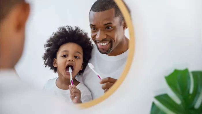 A Dad and child with the child holding a toothbrush 