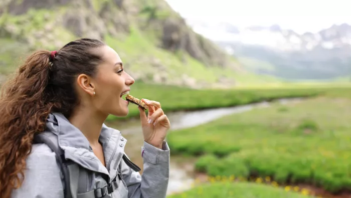 Lady hiking and eating cereal bar