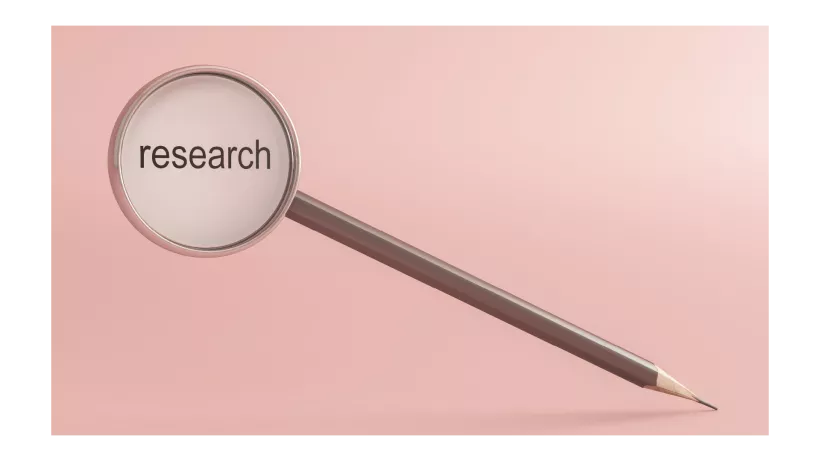A pencil adjoined to a magnifying lass with the word research written in the lens of the magnifying glass