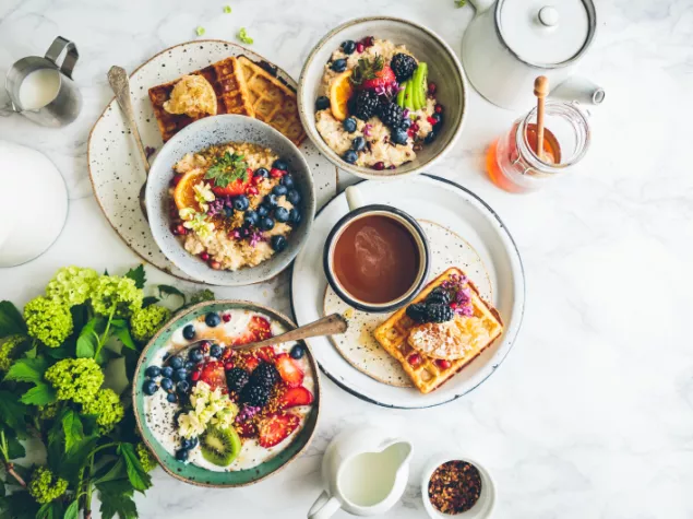 Bowls of cereals and sweet waffles with fruit 