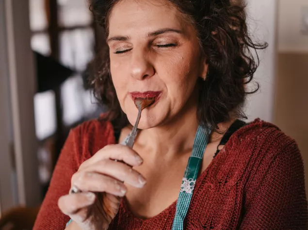 A headshot photo of a lady enjoying the sweet taste of food on a spoon