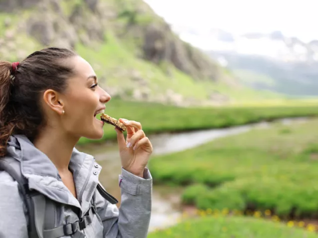 Lady hiking and eating cereal bar