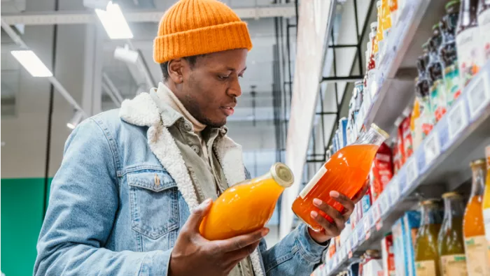 Man in shopping aisle looking at 2 drink bottles