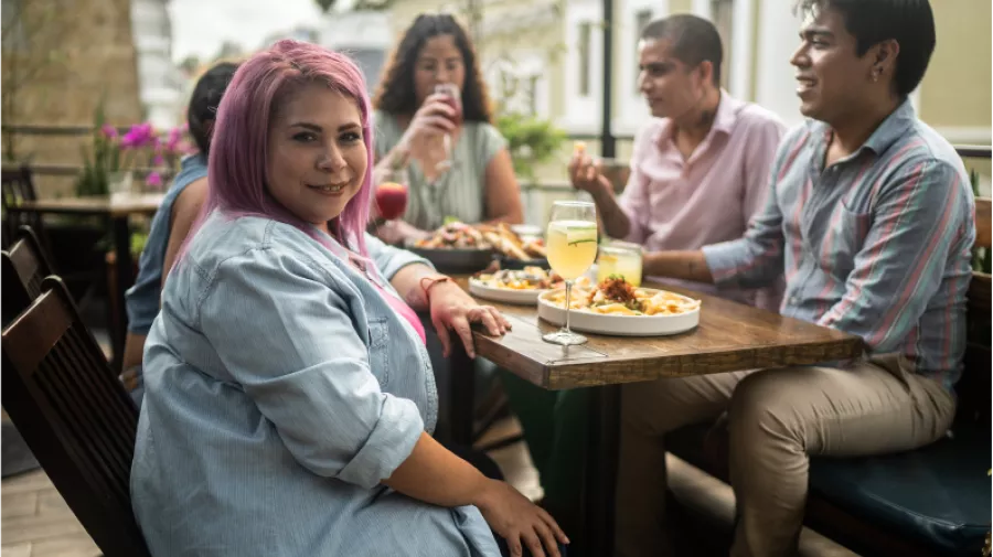 A group of friends sat at a table eating and drinking 